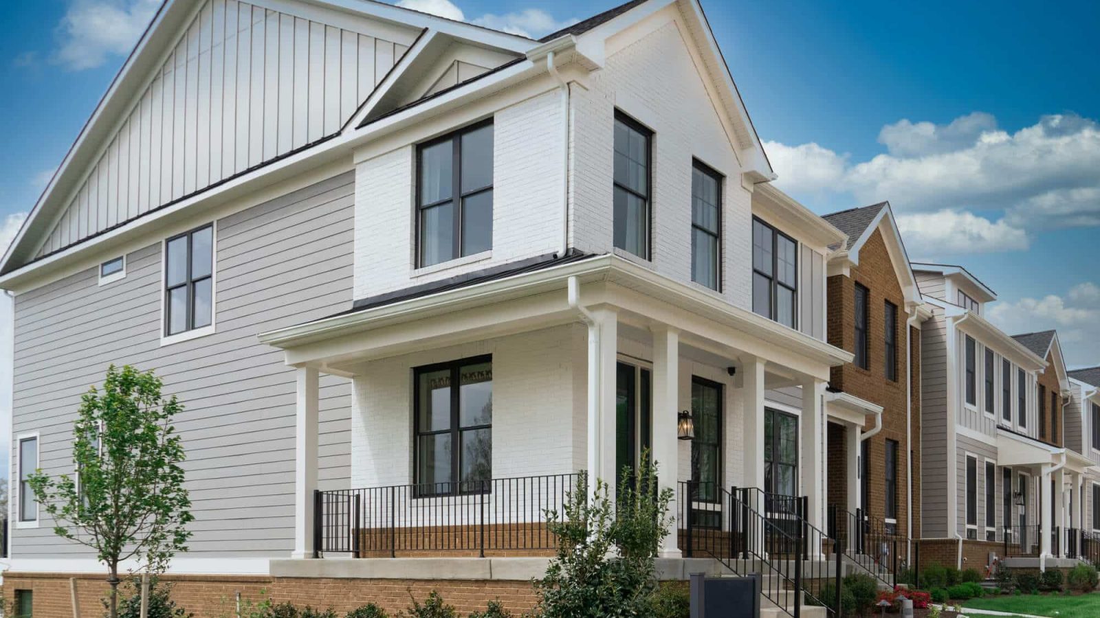Beautiful end unit of a townhome complex with white horizontal vinyl siding