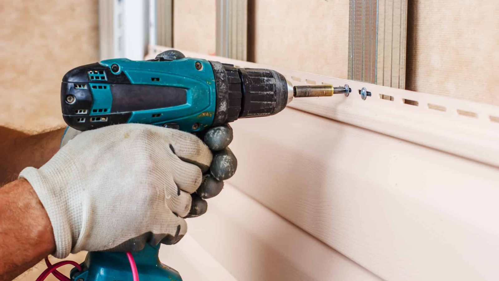 man screwing down vinyl siding
