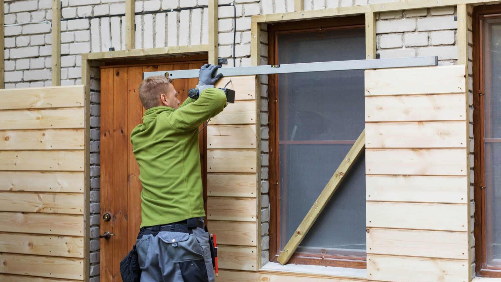 man installing new siding over brick siding